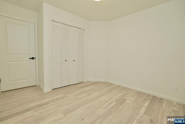 unfurnished bedroom with a closet and light wood-type flooring