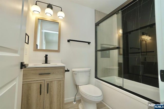 full bathroom with vanity, wood-type flooring, shower / bath combination with glass door, and toilet