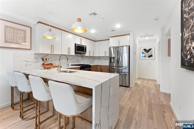 kitchen featuring sink, hanging light fixtures, kitchen peninsula, stainless steel appliances, and white cabinets