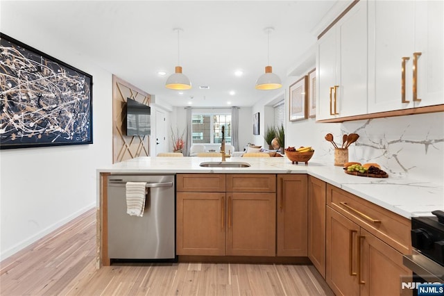 kitchen featuring stainless steel dishwasher, decorative light fixtures, sink, and light wood-type flooring