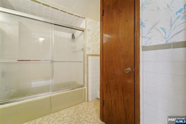 bathroom with tile patterned floors, combined bath / shower with glass door, and tile walls