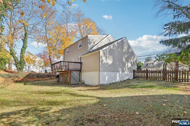 rear view of house with a wooden deck and a lawn