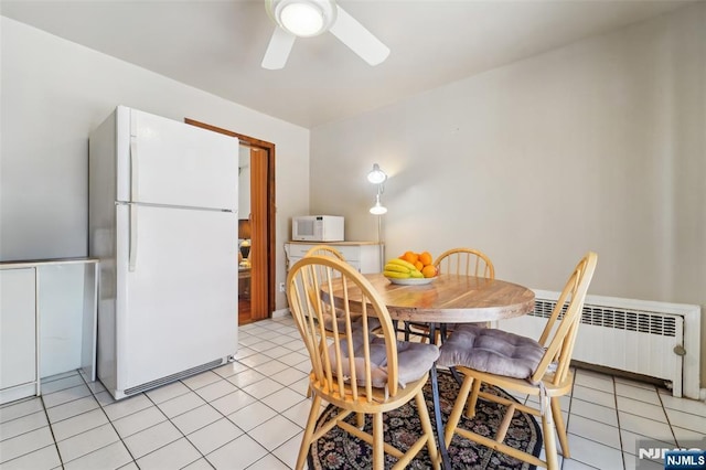 tiled dining room featuring radiator heating unit and ceiling fan