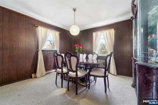 dining area featuring light colored carpet, a baseboard heating unit, and wood walls