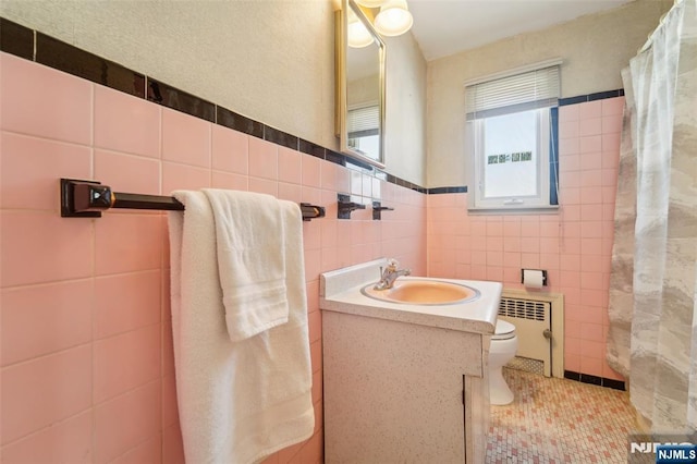 bathroom featuring tile walls, tile patterned flooring, radiator heating unit, vanity, and toilet