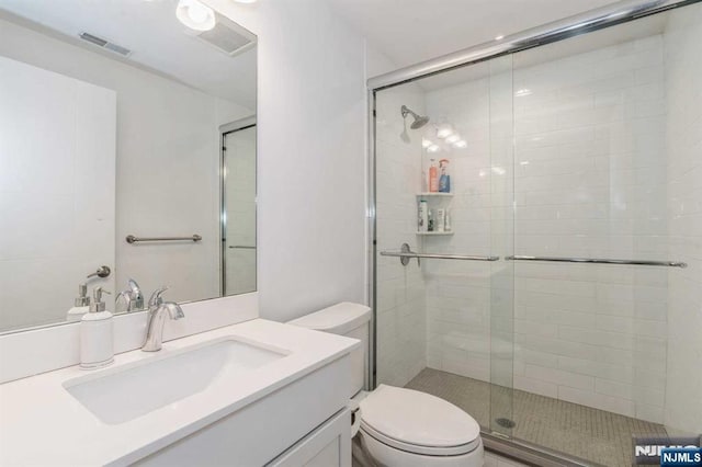 bathroom with vanity, a shower with door, and toilet