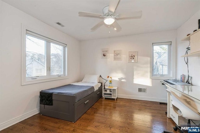 bedroom featuring dark hardwood / wood-style flooring, multiple windows, and ceiling fan