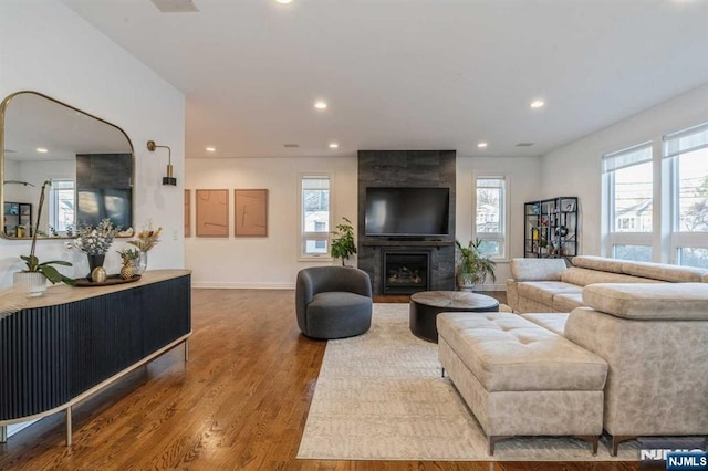 living room featuring wood-type flooring and a tiled fireplace