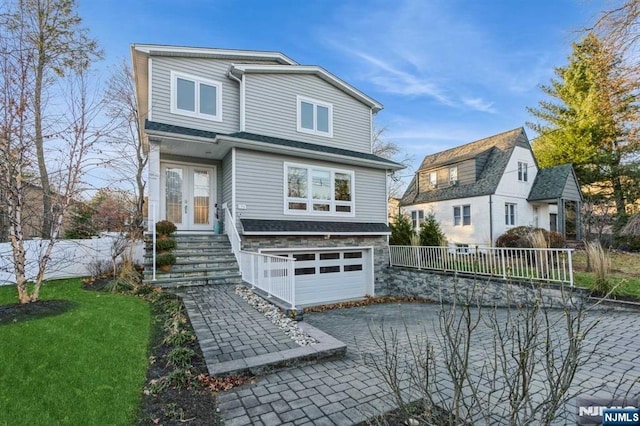 front facade featuring a garage, french doors, and a front lawn