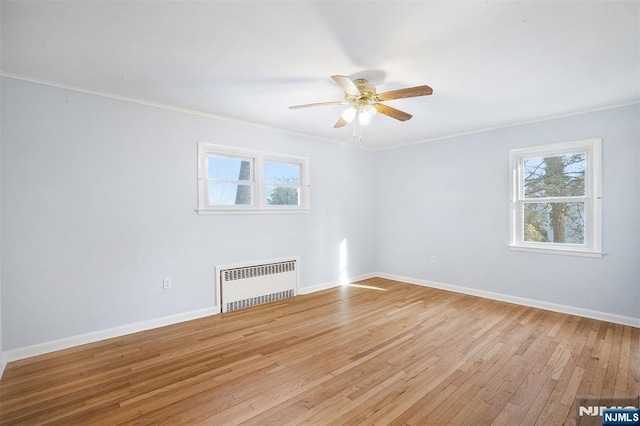 spare room with ceiling fan, ornamental molding, radiator, and light wood-type flooring