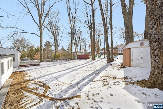 yard layered in snow featuring a shed