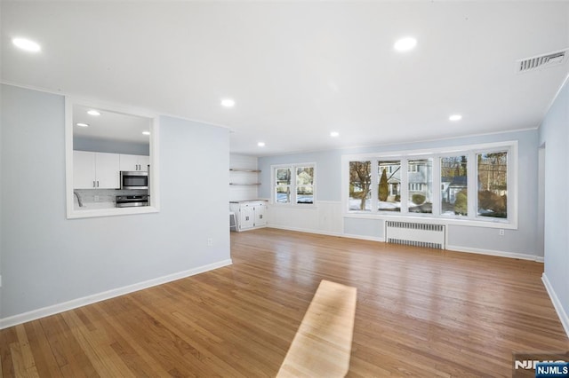 unfurnished living room featuring light hardwood / wood-style flooring and radiator heating unit