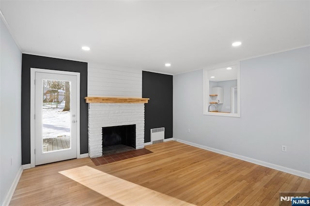 unfurnished living room featuring radiator, a fireplace, and light wood-type flooring