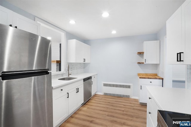 kitchen with radiator, sink, white cabinets, and appliances with stainless steel finishes