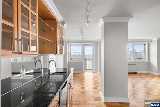 kitchen with dark stone countertops, sink, crown molding, and plenty of natural light