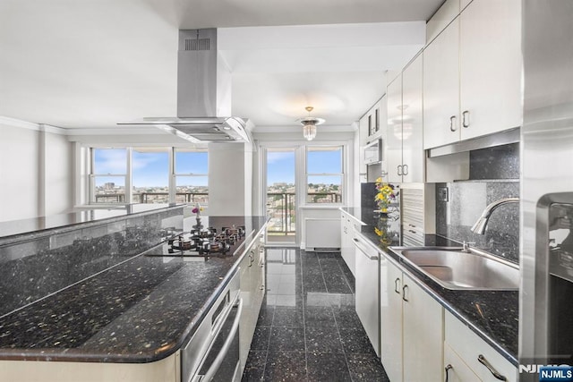 kitchen with sink, appliances with stainless steel finishes, white cabinetry, dark stone countertops, and island range hood