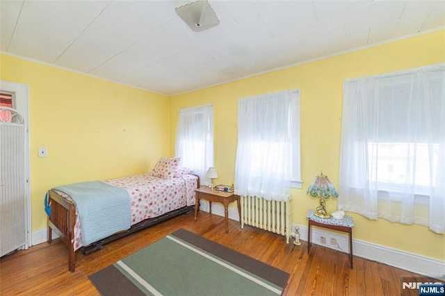 bedroom with radiator and hardwood / wood-style floors