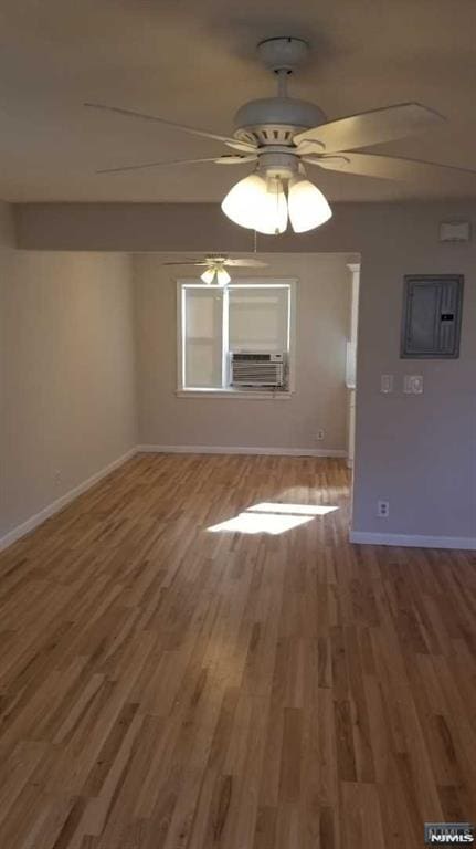 interior space featuring cooling unit, ceiling fan, wood-type flooring, and electric panel