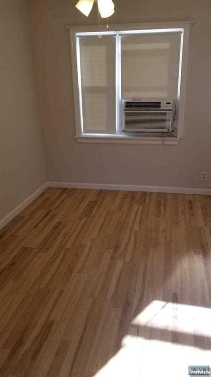 unfurnished room featuring wood-type flooring and cooling unit