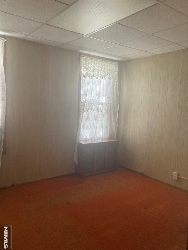 empty room with a paneled ceiling and wooden walls