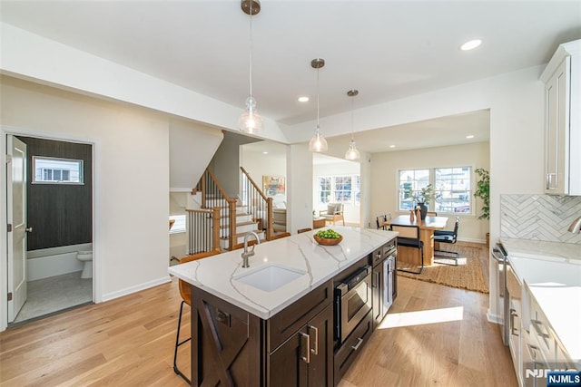 kitchen with sink, white cabinets, light hardwood / wood-style floors, and decorative light fixtures