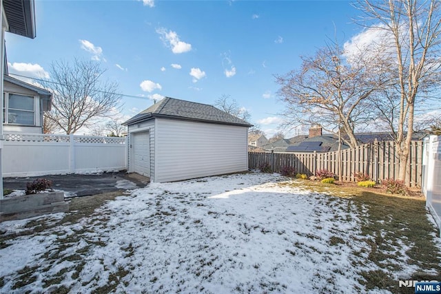 snowy yard featuring a garage and an outdoor structure