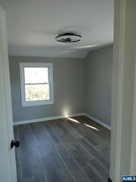 unfurnished room with dark wood-style flooring and baseboards