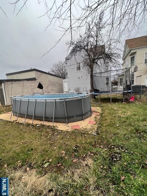 view of pool featuring a trampoline and a lawn