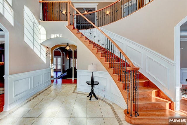 stairway with a towering ceiling and tile patterned floors