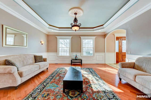 living room featuring ornamental molding, a raised ceiling, and light hardwood / wood-style floors