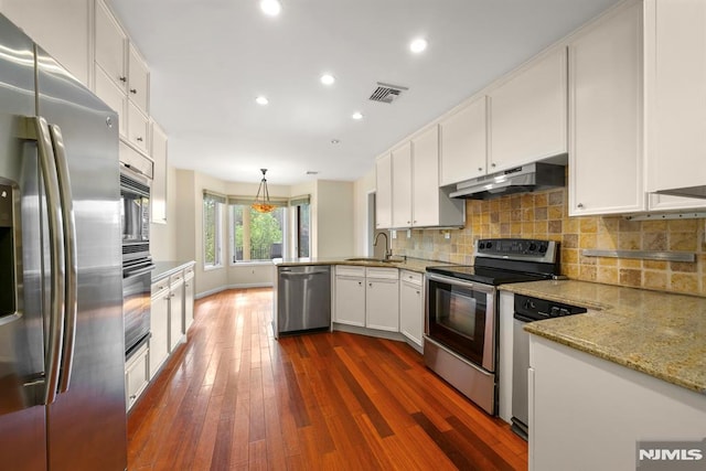 kitchen with dark wood-type flooring, white cabinetry, hanging light fixtures, appliances with stainless steel finishes, and light stone countertops