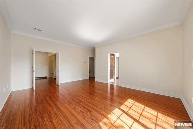 empty room featuring ornamental molding and hardwood / wood-style floors