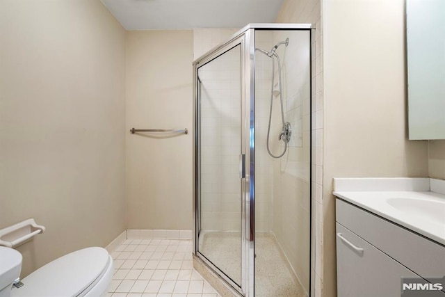 bathroom featuring tile patterned flooring, toilet, vanity, and a shower with shower door