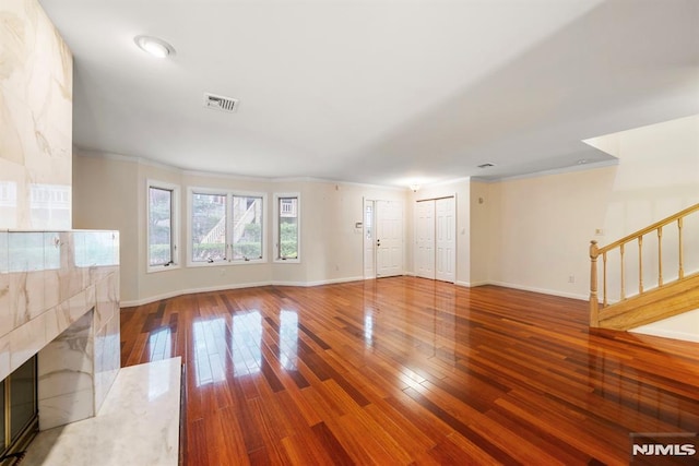 unfurnished living room featuring hardwood / wood-style flooring, a premium fireplace, and crown molding