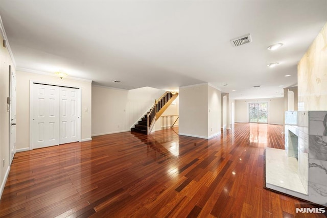 unfurnished living room featuring crown molding, a premium fireplace, and dark hardwood / wood-style floors