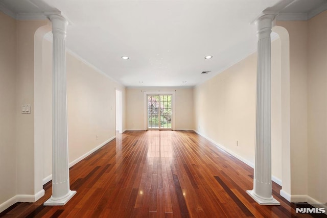 spare room with decorative columns, crown molding, and dark hardwood / wood-style flooring