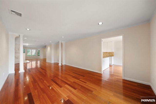 unfurnished room featuring wood-type flooring and ornate columns