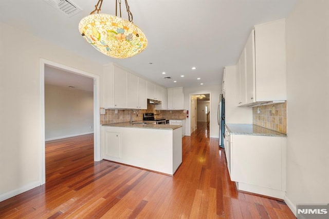 kitchen featuring sink, white cabinetry, hanging light fixtures, appliances with stainless steel finishes, and hardwood / wood-style flooring