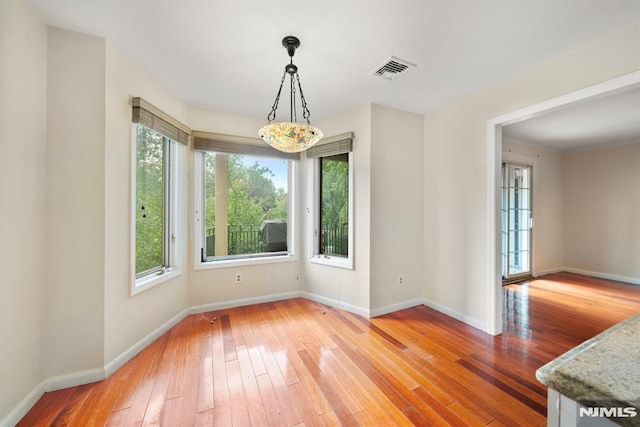 unfurnished dining area with hardwood / wood-style floors and plenty of natural light