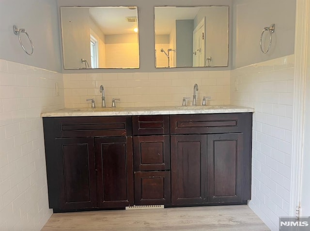 bathroom with hardwood / wood-style flooring, vanity, and tile walls