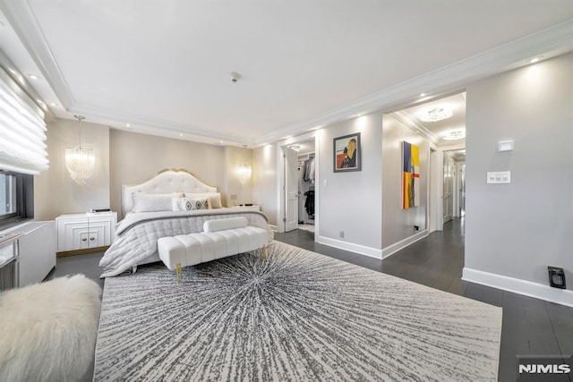 bedroom with dark wood-type flooring, a spacious closet, a chandelier, ornamental molding, and a closet