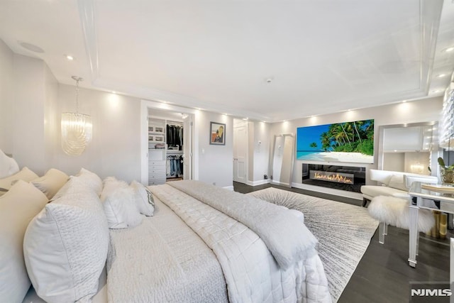 bedroom with a walk in closet, hardwood / wood-style floors, a closet, and a notable chandelier