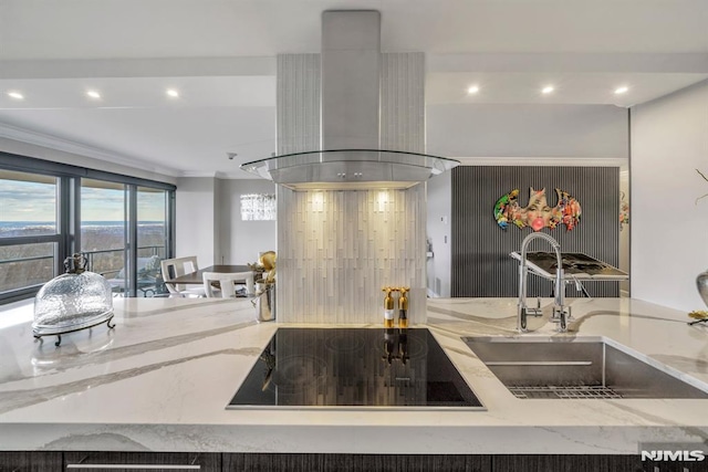 kitchen featuring sink, crown molding, island range hood, light stone countertops, and black electric cooktop