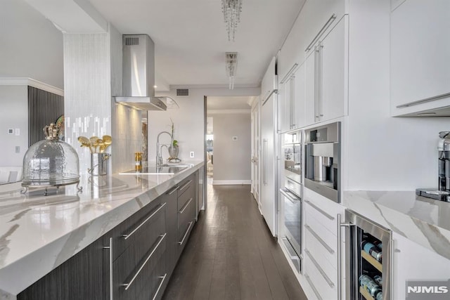 kitchen featuring wine cooler, white cabinetry, light stone counters, ventilation hood, and ornamental molding