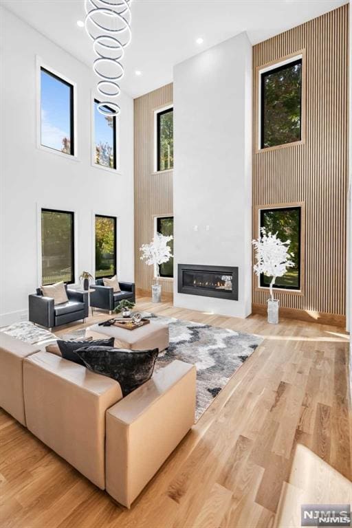 living room with a high ceiling, an inviting chandelier, and light hardwood / wood-style flooring