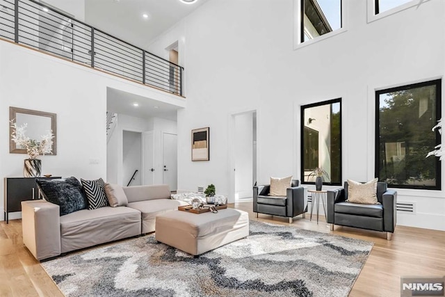 living room featuring light wood-type flooring, a healthy amount of sunlight, and a high ceiling