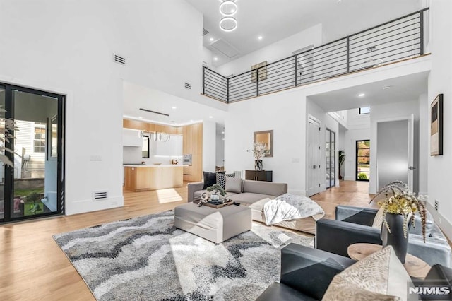 living room featuring light hardwood / wood-style flooring, a towering ceiling, and plenty of natural light