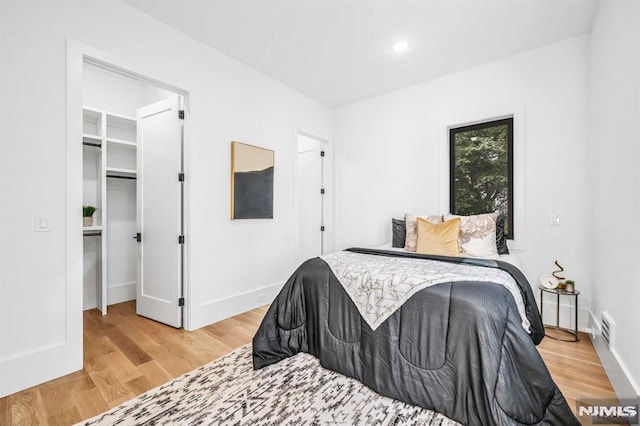 bedroom with a spacious closet, a closet, and hardwood / wood-style flooring