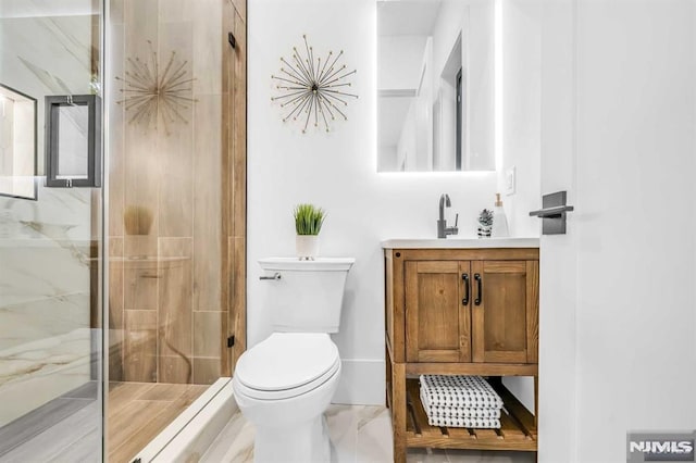 bathroom featuring vanity, a shower with shower door, and toilet