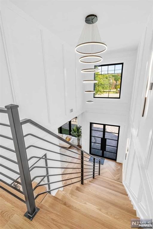 stairway with parquet flooring, a chandelier, and french doors